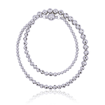 A twisted silver beaded necklace with a graduated design, featuring varying sphere sizes. Can be worn in its twisted form for a layered look or untwisted for a sleek, minimal style.